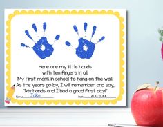 an apple sitting next to two handprints on a white table with a pen