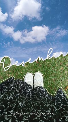 a pair of white shoes sitting on top of a lush green field under a blue sky