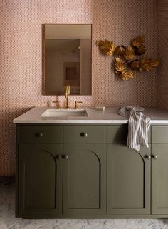 a bathroom with a sink, mirror and wall papered in gold leaf designs on the walls