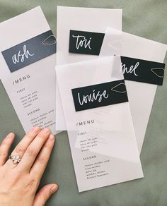 four different types of wedding menus with black and white lettering on them, one being held by a woman's hand