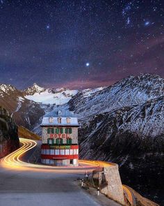 a long exposure shot of a mountain road at night with the stars in the sky