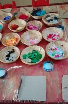 several baskets filled with different colored items on top of a wooden table next to paintbrushes