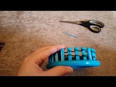 a person holding a blue comb and scissors on the floor next to some other items