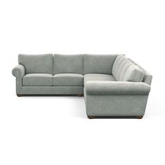 a large sectional couch with a footstool on the left side and a small ottoman on the right