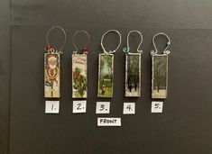 four different sized tags hanging from hooks on a black surface with numbers and pictures attached to them