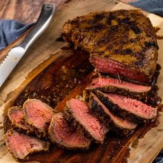 sliced steak on cutting board next to knife and fork