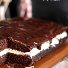 a piece of chocolate cake with white frosting on a cutting board next to a fork