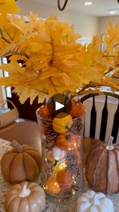 a vase filled with lots of pumpkins on top of a table