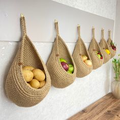 there are three baskets hanging on the wall with fruit in them and one is filled with potatoes