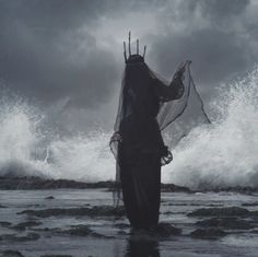 a woman standing on top of a beach next to the ocean under a cloudy sky