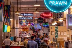 a group of people walking through a store filled with neon signs and food items in front of them