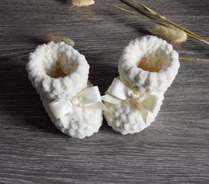 a pair of white baby booties sitting on top of a wooden table