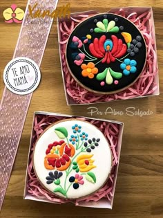 two decorated cookies in boxes on a table