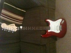 a red guitar sitting on top of a couch