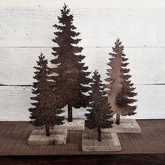 two metal pine trees on concrete bases in front of a white painted wood plank wall