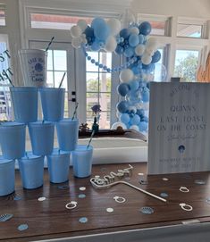 a table with blue cups and balloons on it