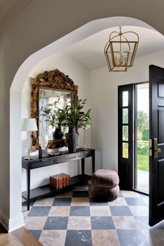 an entry way with a mirror, stool and potted plant on the table in front of it