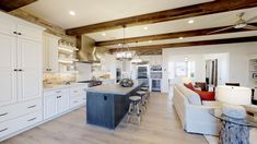 a large open concept kitchen with white cabinets and wood beams on the ceiling, along with bar stools