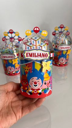 a hand holding a small cup with cartoon characters on it and three other cups in the background