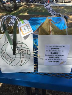 two shopping bags sitting on top of a blue bench next to each other with writing on them