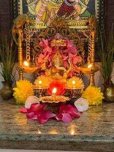 an idol with flowers and candles in front of it