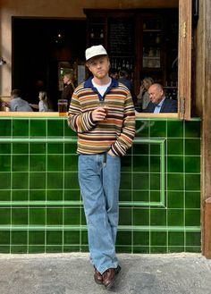 a man standing in front of a green tiled bar with his hands on his hips