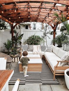 a little boy standing on top of a wooden bench next to a white couch and table