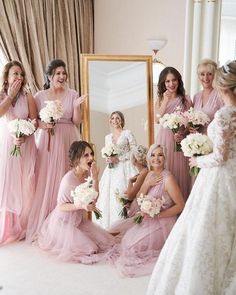 a group of bridesmaids pose for a photo in front of a mirror with their bouquets