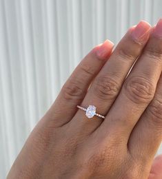 a woman's hand with a diamond ring on top of her finger and the other hand holding an engagement ring