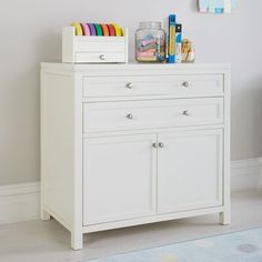 a small white cabinet with many items on it's top shelf in a child's room