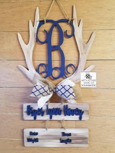 a wooden sign with antlers on it and the letter b in blue is hanging from a rope