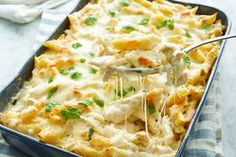 a casserole dish with chicken and cheese being scooped from the casserole