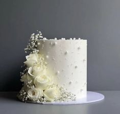 a white wedding cake decorated with flowers and baby's breath on a gray background