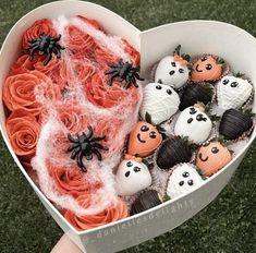 a heart shaped box filled with halloween cupcakes on top of a green field