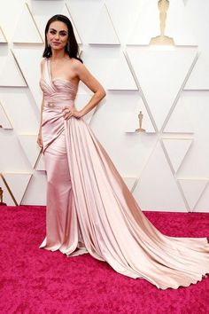 a woman in a pink gown posing on the red carpet at an oscars event