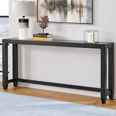 a black console table sitting in front of a window with a painting on the wall