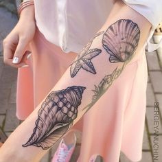 a woman's arm with seashells and flowers tattoo on her left forearm