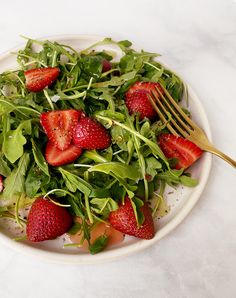 a white plate topped with salad and strawberries