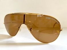 Rare vintage Ray Ban by Bausch and Lomb Wings Ambermatic sunglasses. Made in the 80s in the USA.  gold metal frame with bar Unisex B&L G-15 lenses Condition: very good condition, they have a scratch on the left part, shown on pictures. It does not affect vision and not visible when worn. Original case included - not closing , another generic case will be provided as well. Measurements:  -Total width:  145mm / 5.708inches  -Temple length: 125mm / 4.92inches  -Height: 60mm / 2.36inches  -Lense wid Retro Gold Shield Sunglasses With Uv Protection, Retro Gold Aviator Sunglasses With Mirrored Lenses, Vintage Gold Sunglasses For Summer, Retro Gold Shield Sunglasses With Mirrored Lenses, Vintage Brown Aviator Sunglasses, Retro Gold Aviator Sunglasses With Gradient Lenses, Retro Gold Sunglasses With Uv Protection, Retro Gold Shield Sunglasses With Tinted Lenses, Gold Retro Sunglasses With Uv Protection