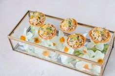 small appetizers are displayed in a glass box with flowers on the bottom and sides