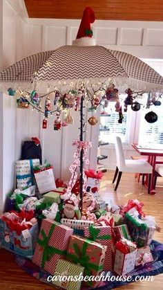 a christmas tree with presents under an umbrella in the middle of a room filled with gifts