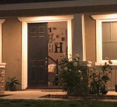 the front door of a house at night with lights on and flowers in pots outside