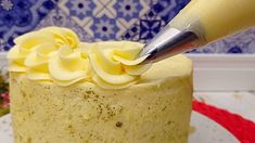 a cake with white frosting and yellow icing is being cut by a knife