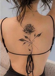 a woman's back with a rose tattoo on it