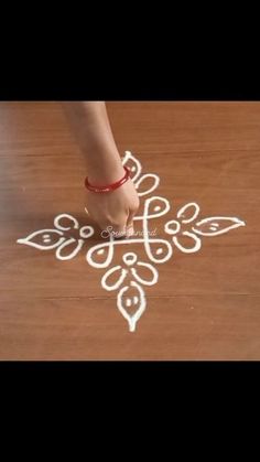 a person standing on top of a wooden floor next to a small white flower design