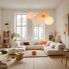 a living room filled with lots of furniture and large white lamps hanging from the ceiling