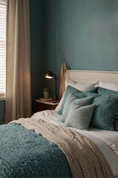 a bedroom with blue walls and white bedding