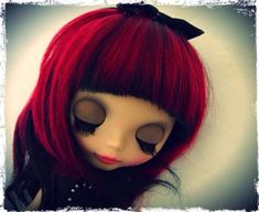 a close up of a doll with long red hair and black eyeliners on her face