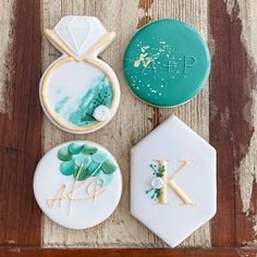 three decorated cookies sitting on top of a wooden table next to green and white icing