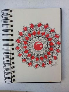 a spiral notebook with red and white designs on it